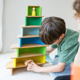 Kind baut Turm mit Regenbogen Motorikspiel von Grimm's aus Holz in Neongrün