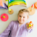 Mädchen hält Figur von Mix aus 3 Grimm's Neonfreunden aus Naturholz