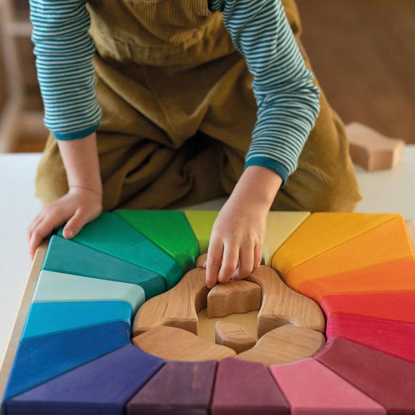 Kind am Spielen mit Grimm's Bauspiel Regenbogenlöwe aus Massivholz