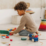 Spielendes Kind mit Nachzieh-Lastwagen von Grimm's im Vordergrund