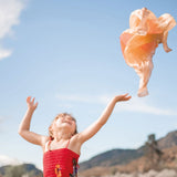 Kind wirft Spielseide "Wüste" von Grimm's in die Luft