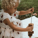 Kind fädelt Holzformen von KAWI Senso auf die Baumwollkordel