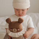 Kind schaut Großen Teddy mit beigem Strampler von Main Sauvage an