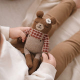 Kind hält Main Sauvage Teddy aus Alpakawolle mit kariertem Hemd