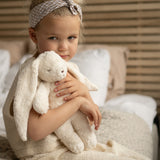 Mädchen mit Moonie Einschlafhilfe und Kuscheltier-Hase im Farbton Organic Polarweiss