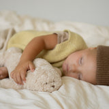 Moonie Einschlafhilfe Robbe Organic Sand in Arm von schlafendem Kind