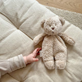Moonie Sensorik-Teddybär im Farbton Organic Sand mit Kinderhand