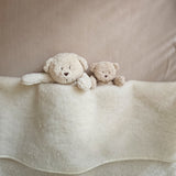 Moonie Sensorik-Teddybär im Farbton Organic Sand unter Decke neben Einschlafbär