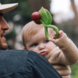 Kind mit Kirschen-Beißring und Rassel von Oli & Carol