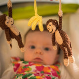 Kinderwagenkette Affe CHARLIE in Braun von SindiBaba mit Baby im Hintergrund