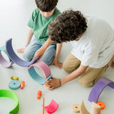 Kinder am Spielen mit Holz Regenbogen Motorikspiel von Grimm's in neonpink