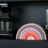 Holz Regenbogen Motorikspiel von Grimm's in neonpink vor schwarzem Hintergrund