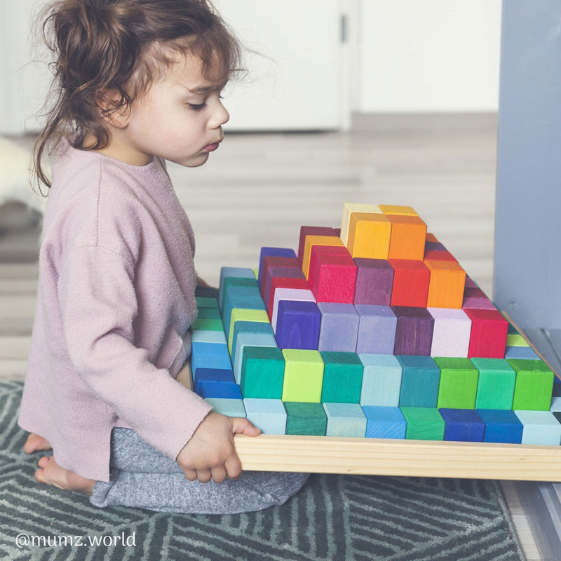 Kind mit Großer Grimm's Stufenpyramide mit 100 Holzbausteinen in Regenbogenfarben