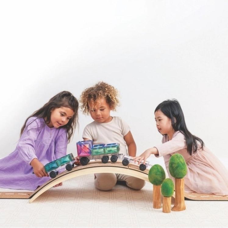 Drei Kinder spielen mit Connetix Magnetbausteine Pastel Transport Pack 50 Teile