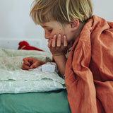 Kind entdeckt eine Überraschung aus dem Grapat Adventskalender 2026 im Bett