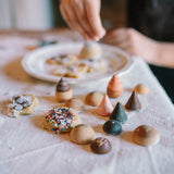 Kind am Backen mit Bakes Holz-Backwaren von Grapat im Vordergrund