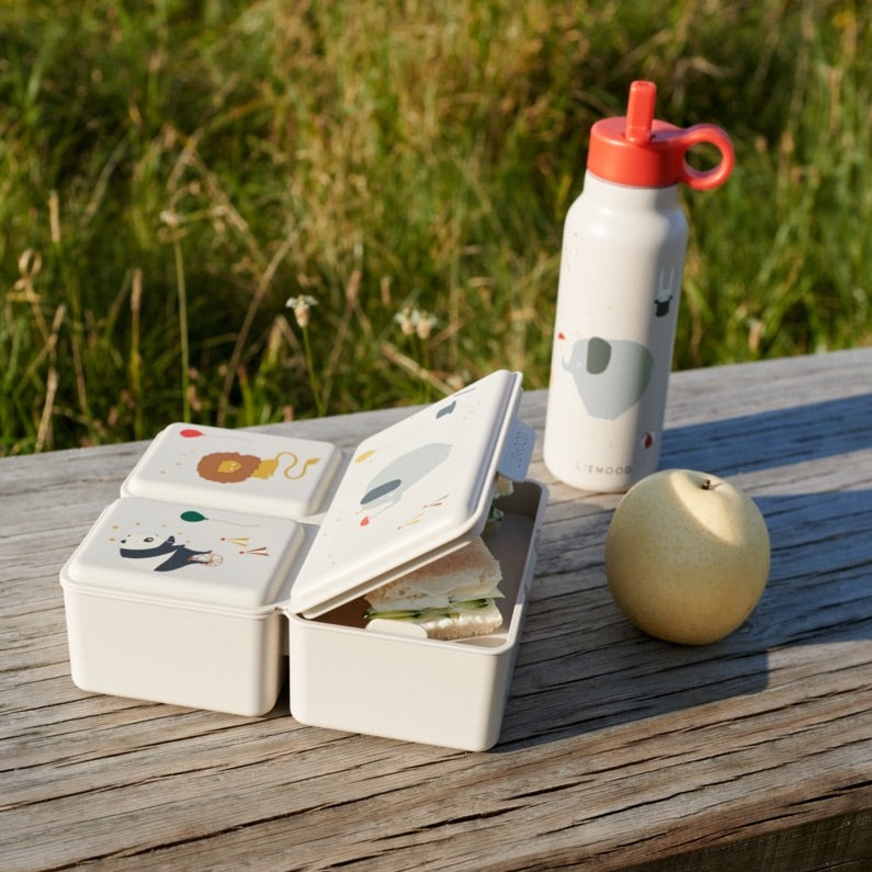 Lunchbox Driss von Liewood in Safari-Design draußen auf Tisch stehend