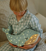 Kind mit Little Lights Kinderlampe Wal im Farbton Lagoon Waves