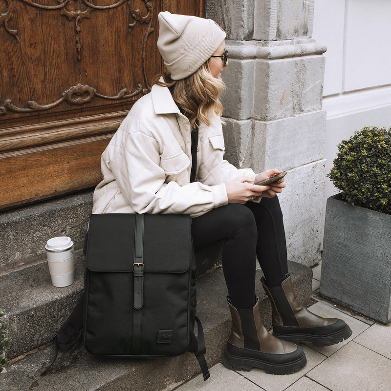 Frau sitzt auf Hauseingang mit Wickelrucksack Linea Black von Little Who