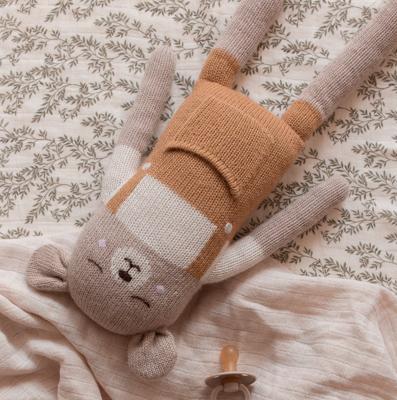Großer auf Bett liegender Teddy aus Alpakawolle mit senffarbener Latzhose von Main Sauvage
