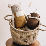 Großer Teddy aus Alpakawolle mit senffarbener Latzhose von Main Sauvage in Korb sitzend