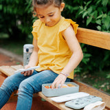 Kind auf Bank mit Montento Lunchbox mit Waschbärenmotiv in minzgrün
