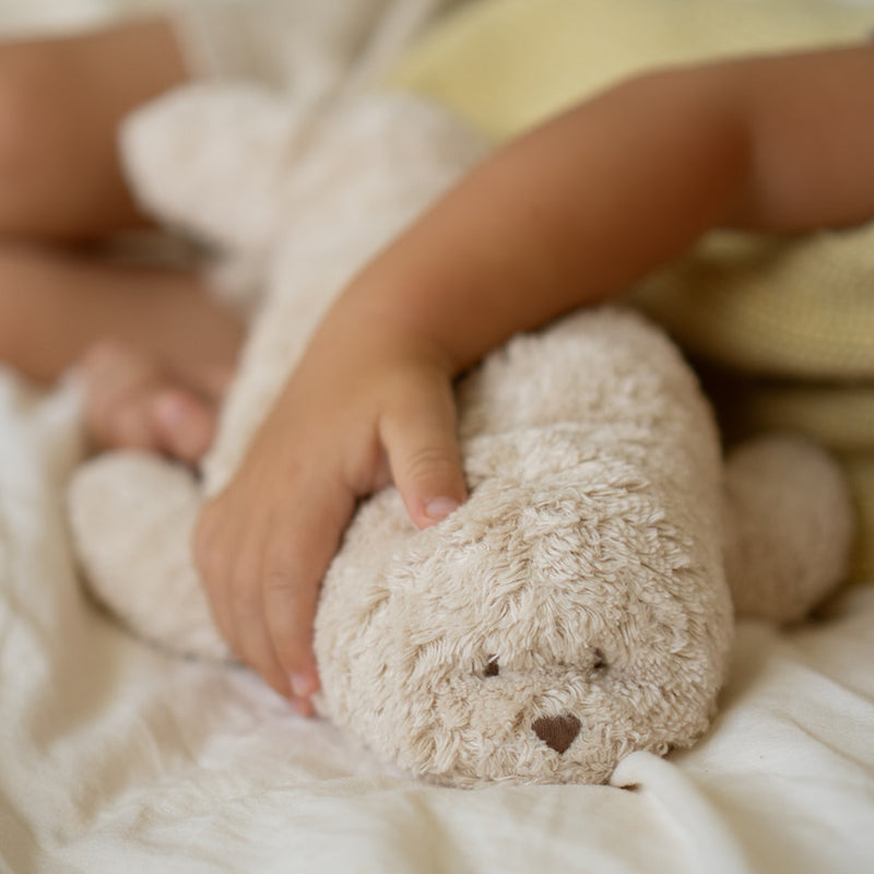 Moonie Einschlafhilfe Robbe Organic Sand von Kinderarm gehalten