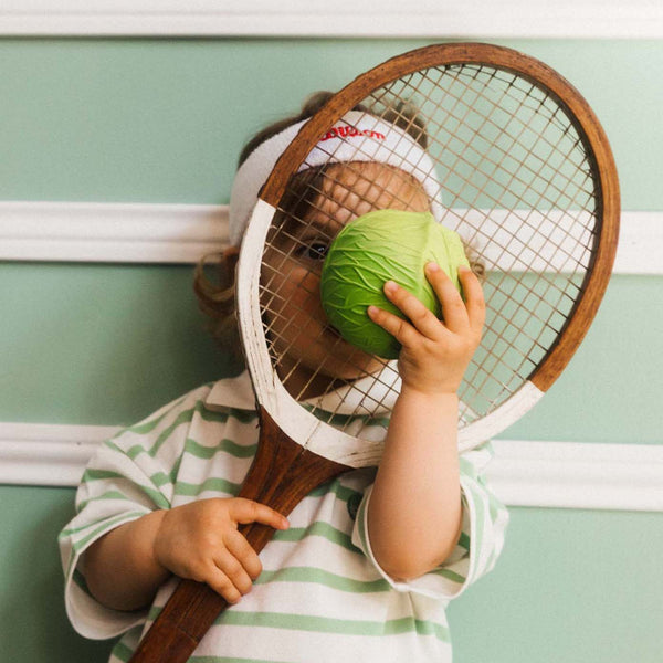 Kind mit Tennisschläger und Sensorikball in Form eines Weißkohls von Oli & Carol