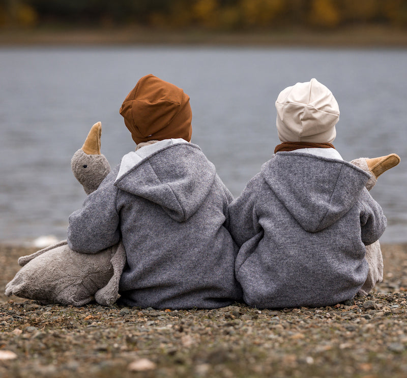 Kinder sitzen draußen mit Kuscheltier-Gänsen von Senger Naturwelt