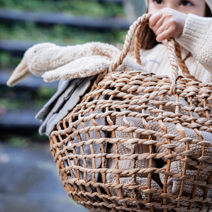 Kleine Gans von Senger Naturwelt im Farbton Leinen wird von Kind in geflochtenem Korb getragen
