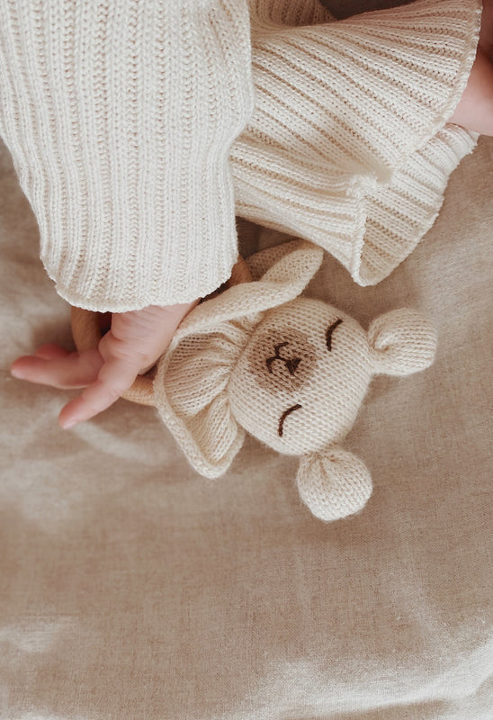 Hand von Kleinkind die Bären-Rassel aus Alpaka-Wolle hält