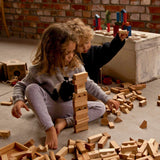 Kinder am Spielen mit Bauklötzen aus Naturholz in Naturfarben on Wooden Story