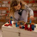 Kind am Spielen mit 50 XL Holz Bauklötzen in Regenbogenfarben von Wooden Story