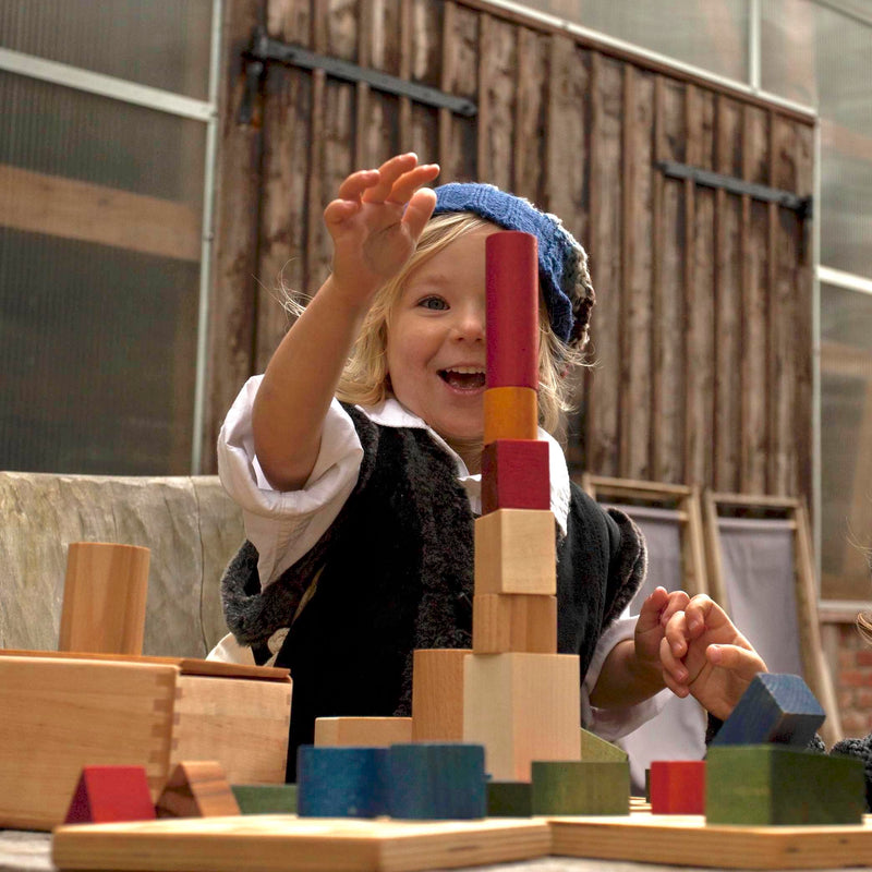 Kind am Spielen mit 30-teiligem Set an Holzbauklötzen in Regenbogenfarbe von Wooden Story