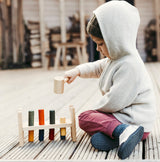 Kind am Spielen mit Holz-Klopfbank von Wooden Story mit Hammer und bunten Holz-Zapfen
