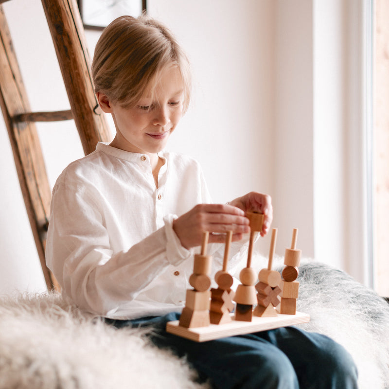 Kind am Spielen mit 26-teiligem Steckspiel aus Naturholz von Wooden Story 